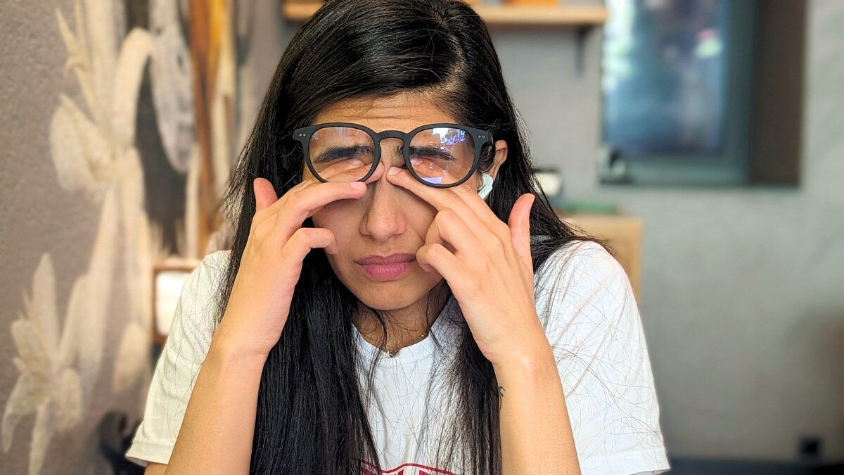 une Femme portant des lunettes, se pinçant l’arête du nez avec une expression de fatigue oculaire.