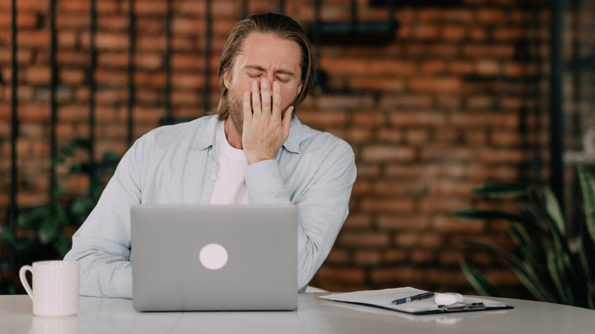 Un homme à son bureau bâille assis devant un ordinateur. Concept de privation de sommeil