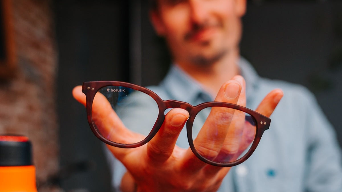 un jeune homme tenant des lunettes horus x